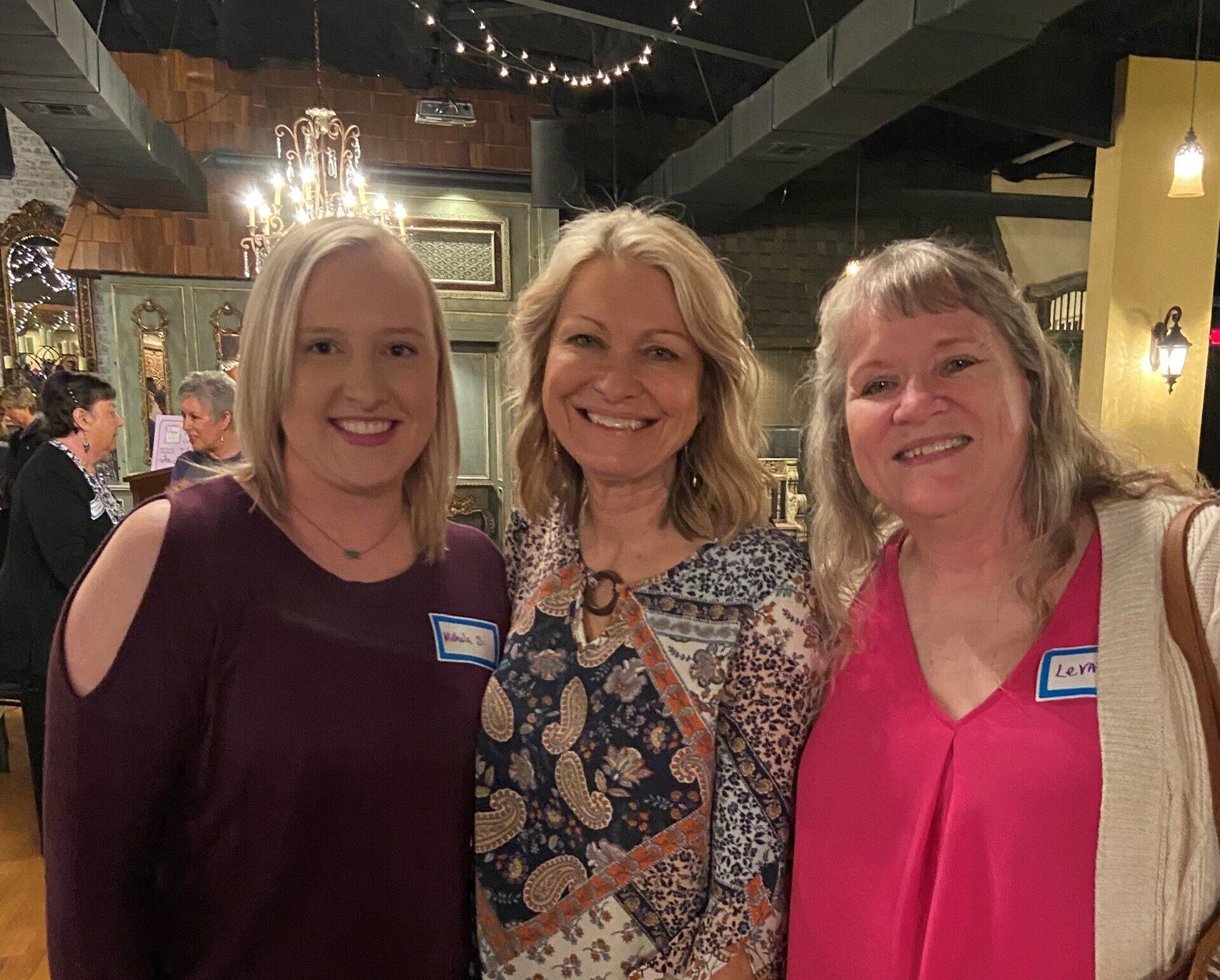 Three women are posing for a picture together in a restaurant.