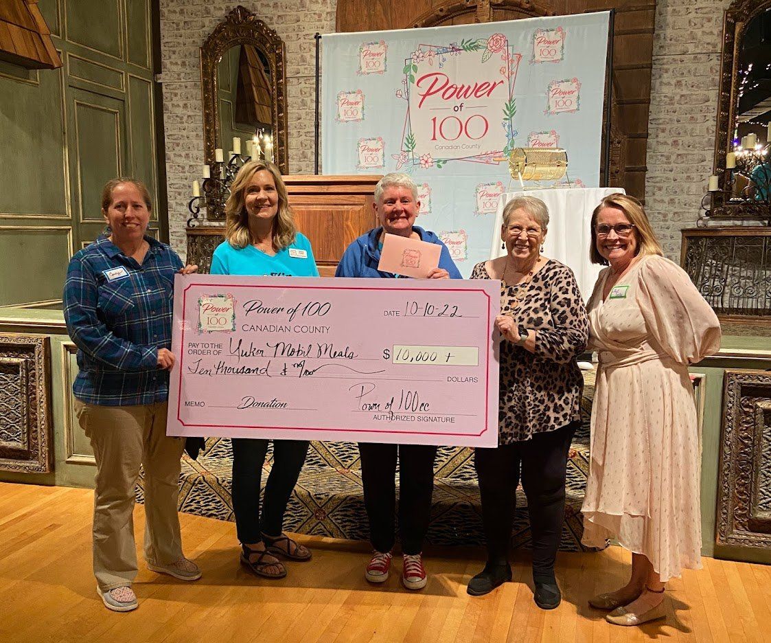 A group of women are standing next to each other holding a large pink check.