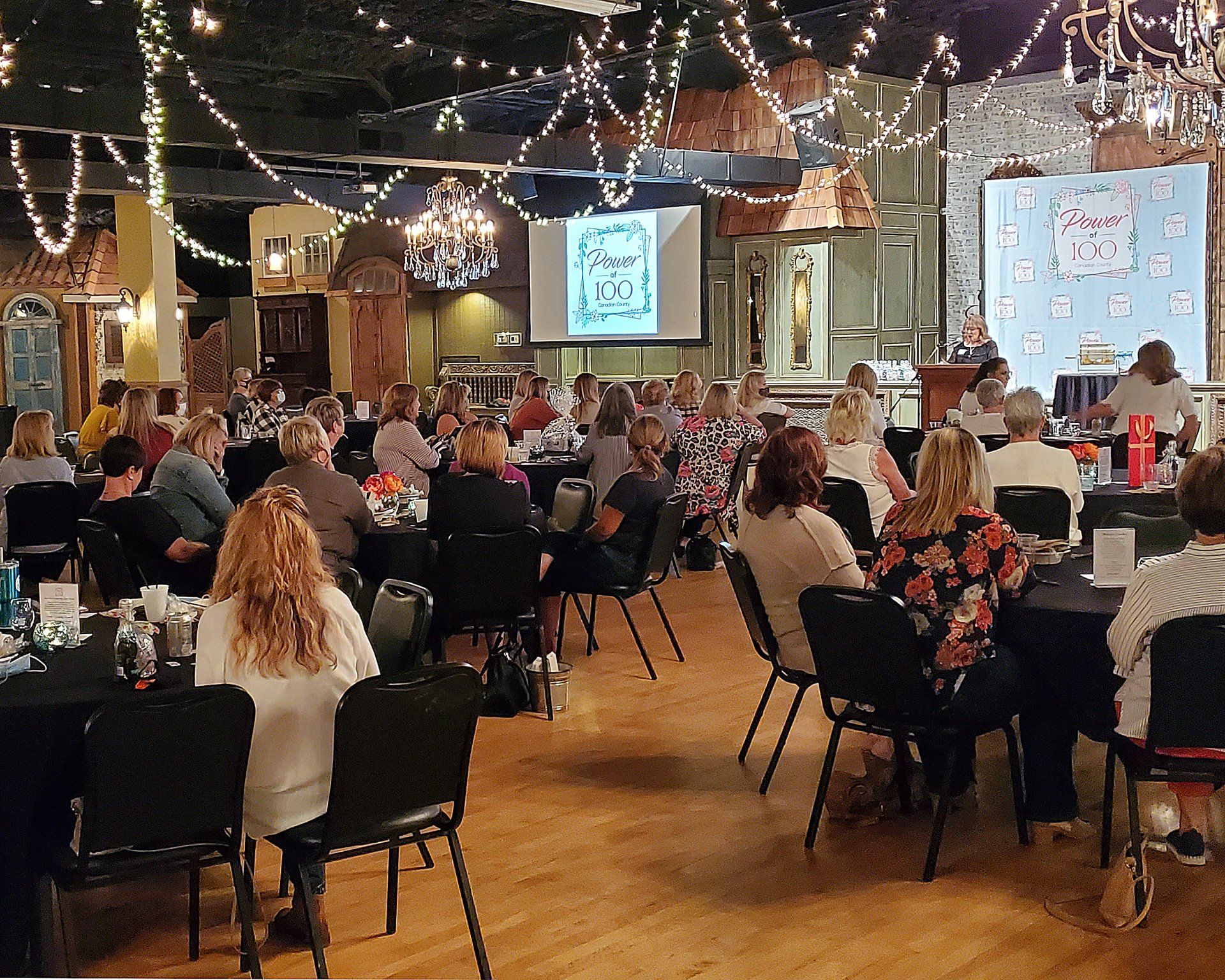 A large group of people are sitting at tables in a large room.