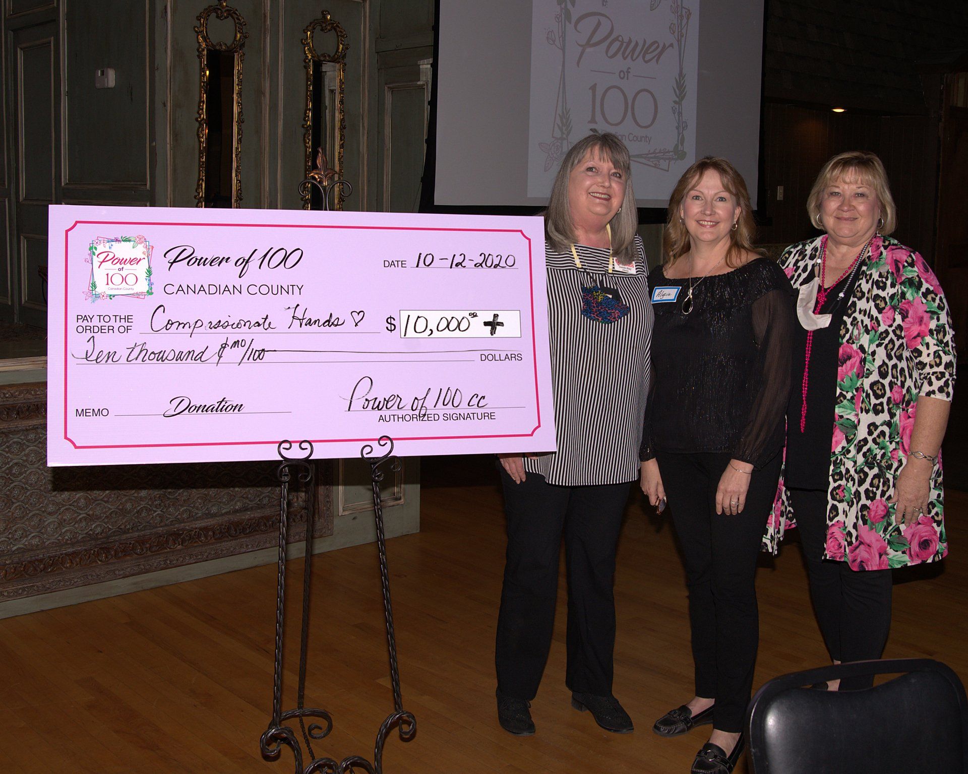 Four women standing in front of a check that says ' power 100 ' on it