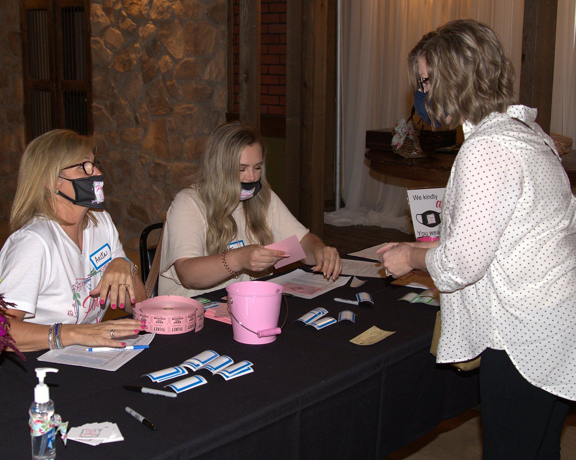 A group of women are sitting at a table with a pink bucket.