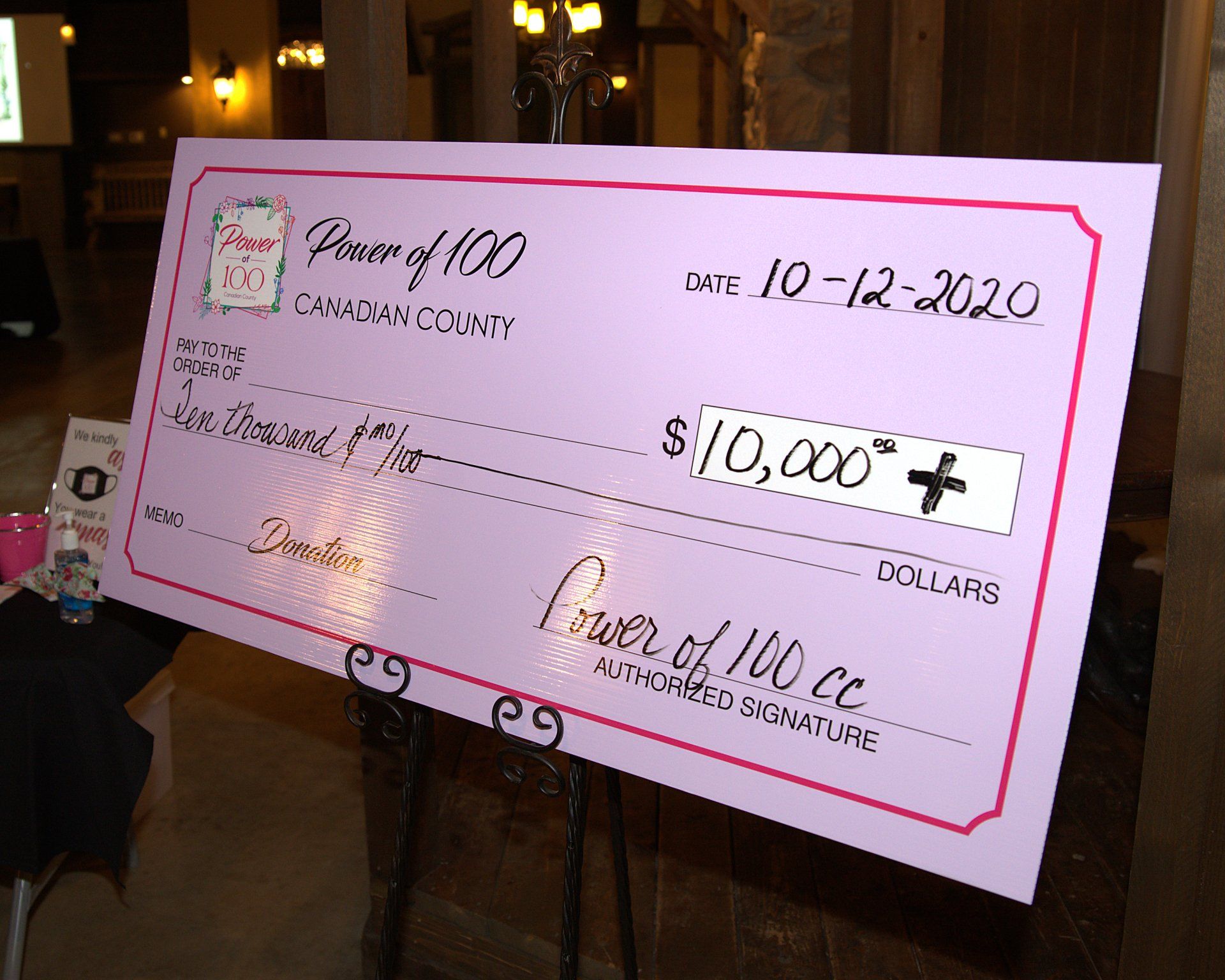 A large pink check that says power of 100 on it