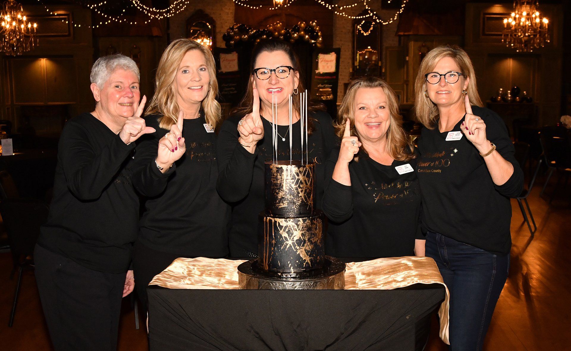 A group of women are standing in front of a cake.