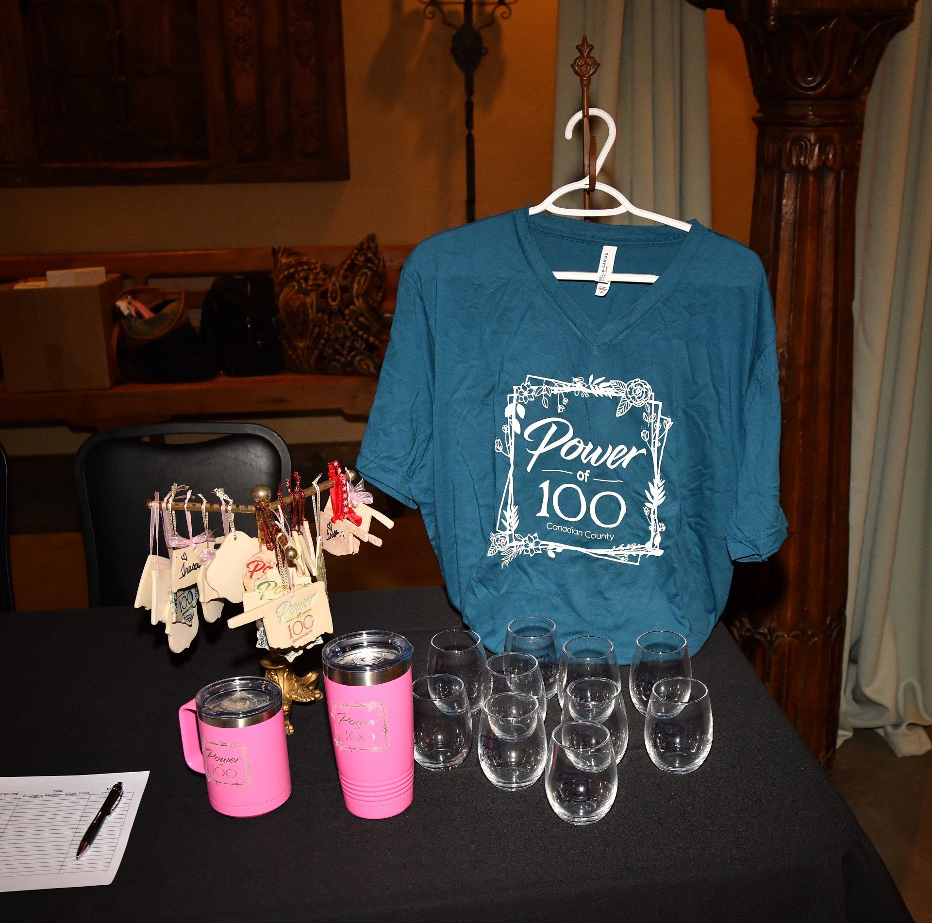 A blue shirt that says power 100 is hanging on a hanger