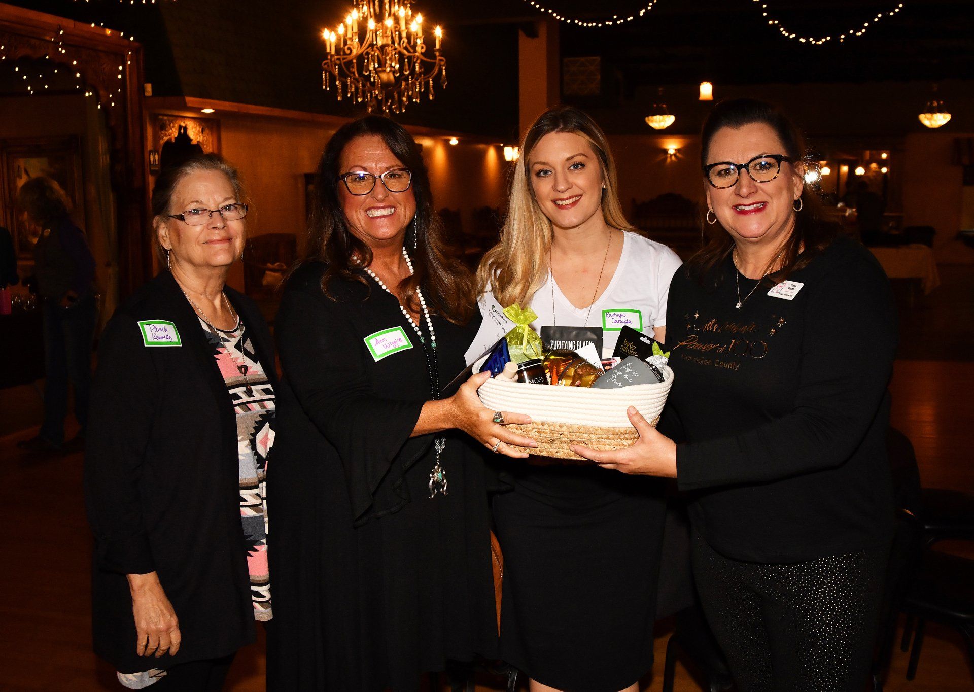 A group of women are standing next to each other holding a basket.