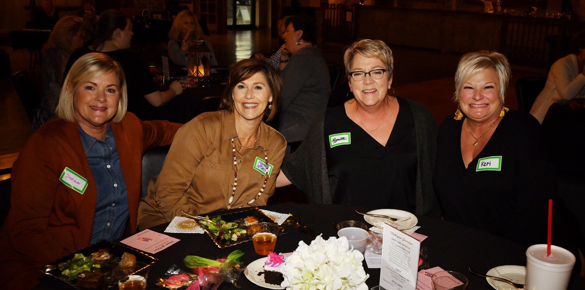 A group of women are sitting at a table with plates of food.
