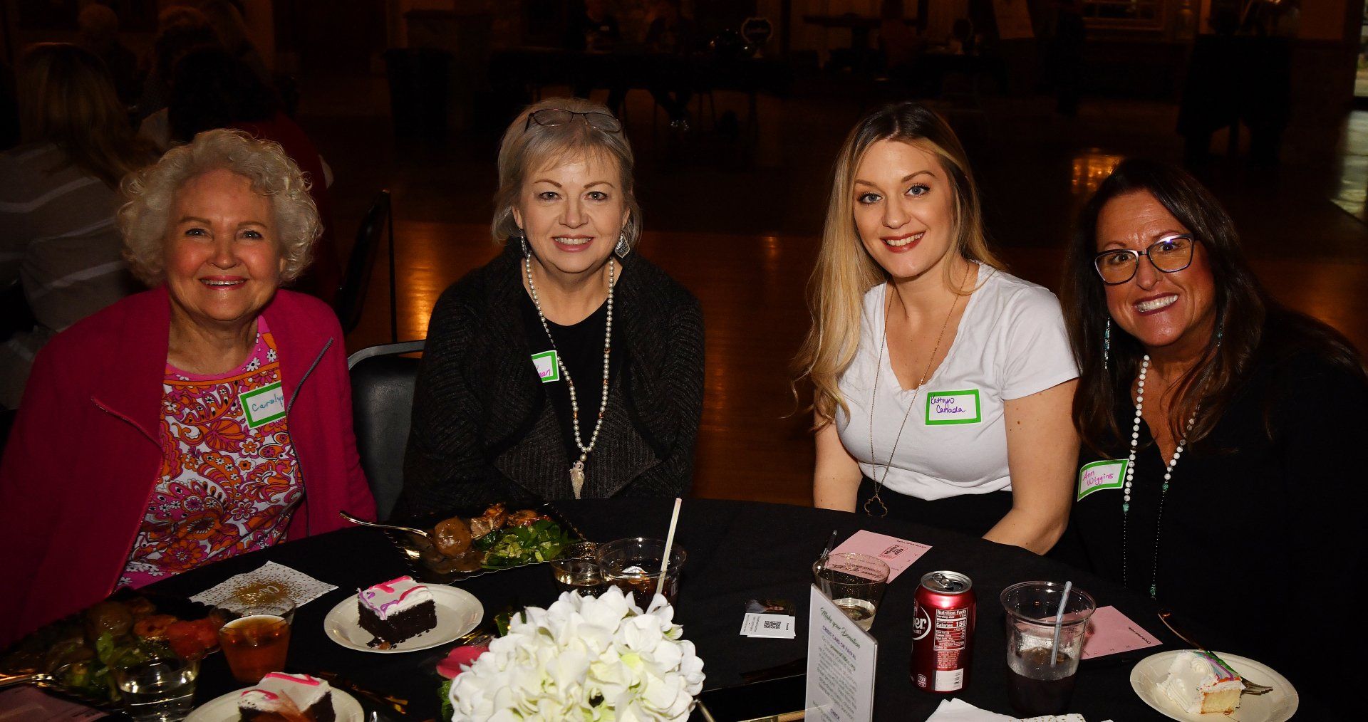 A group of women are sitting at a table with plates of food.