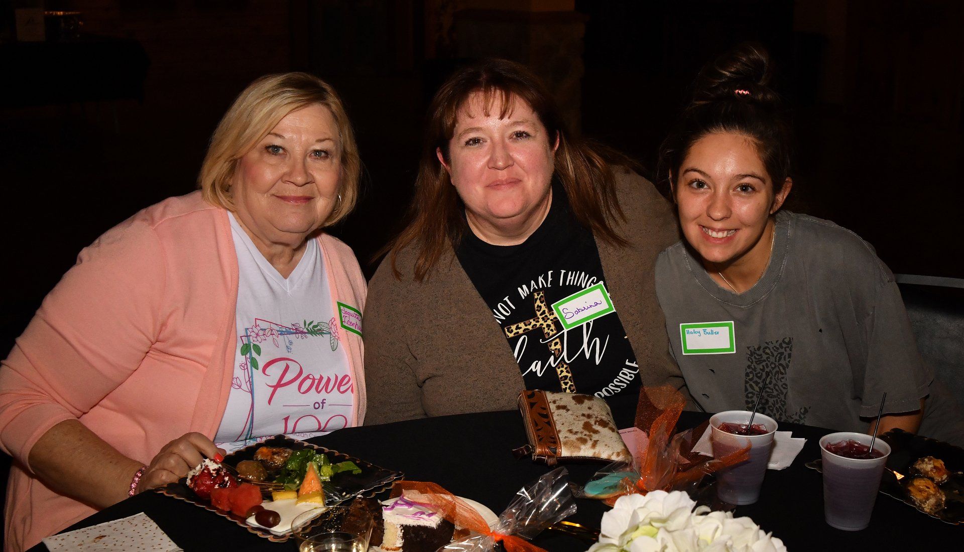 Three women are sitting at a table with plates of food.