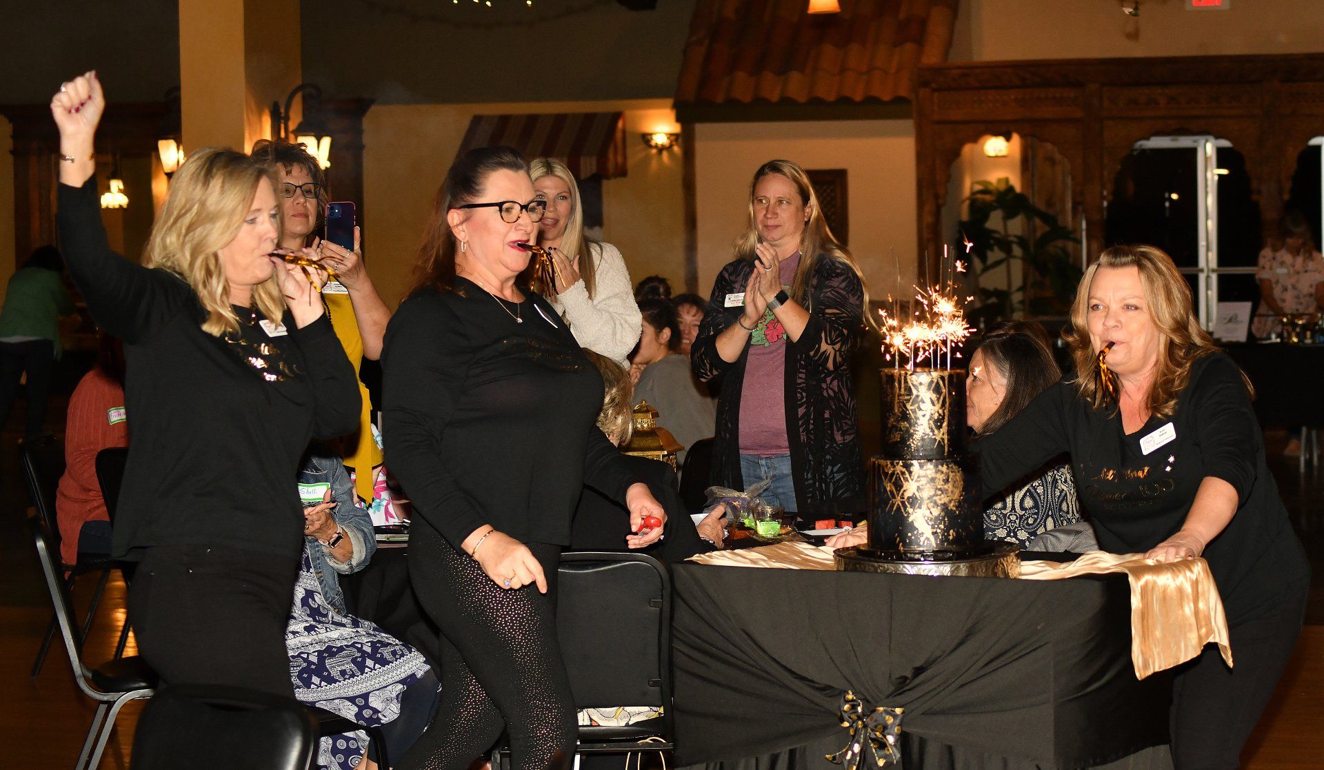 A group of women are standing around a table with a cake on it.