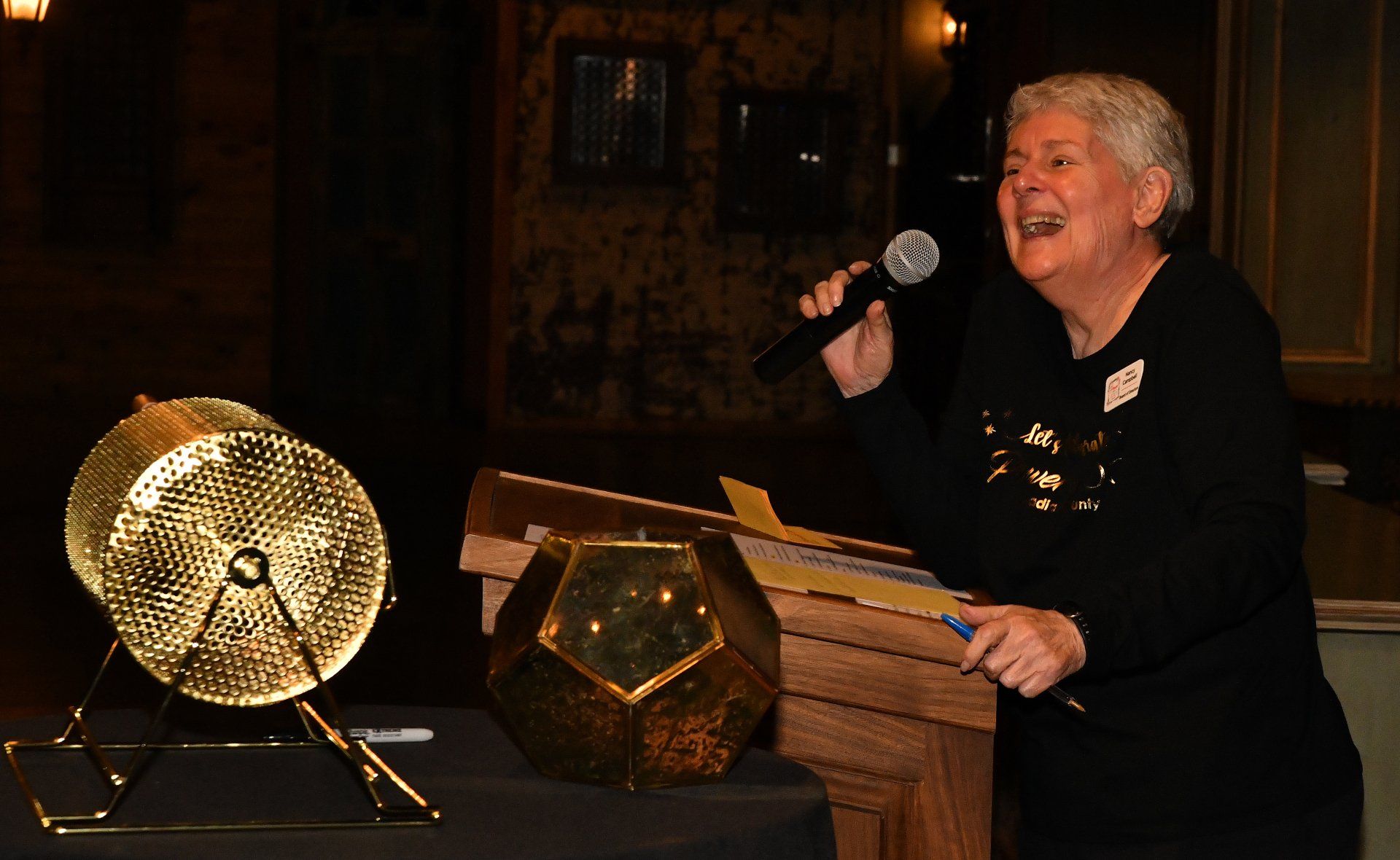 A woman is holding a microphone in front of a lottery wheel.