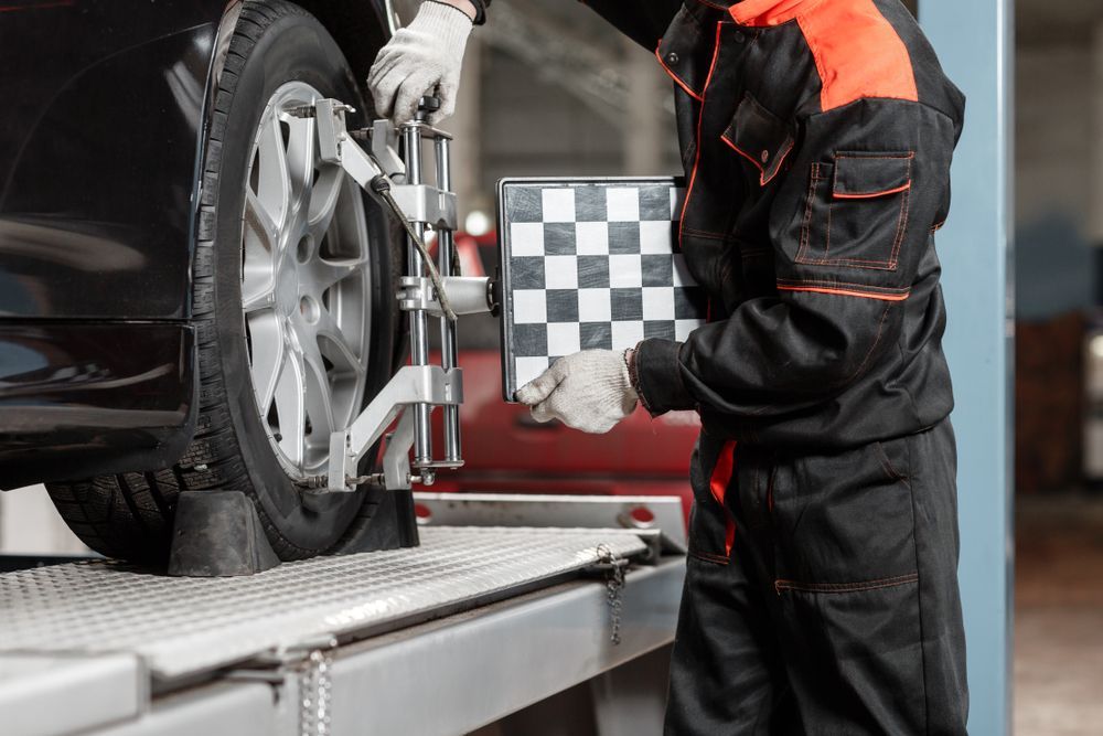 A Man Is Adjusting The Alignment Of A Car Wheel In A Garage — Lyons Street Paint Panel in Cairns, QLD