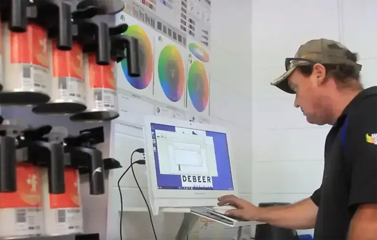 A Man Using a Laptop with The Word Dealer on The Screen— Lyons Street Paint Panel in Bungalow, QLD