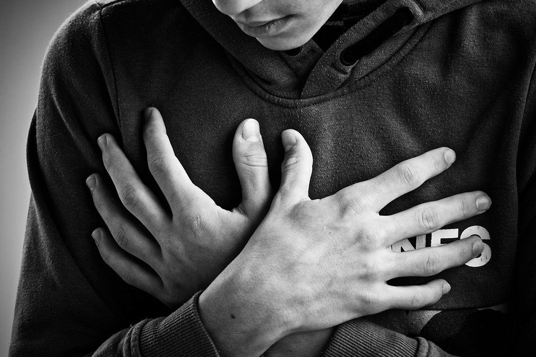 Una fotografía en blanco y negro de una persona que se sostiene el pecho con las manos.