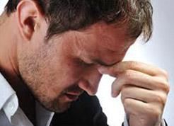 Un hombre sostiene su cabeza entre sus manos.