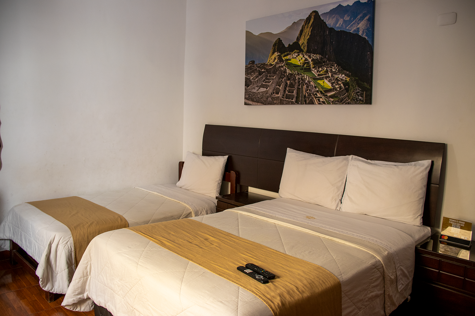 Habitación de hotel con dos camas y una imagen de Machu Picchu en la pared.