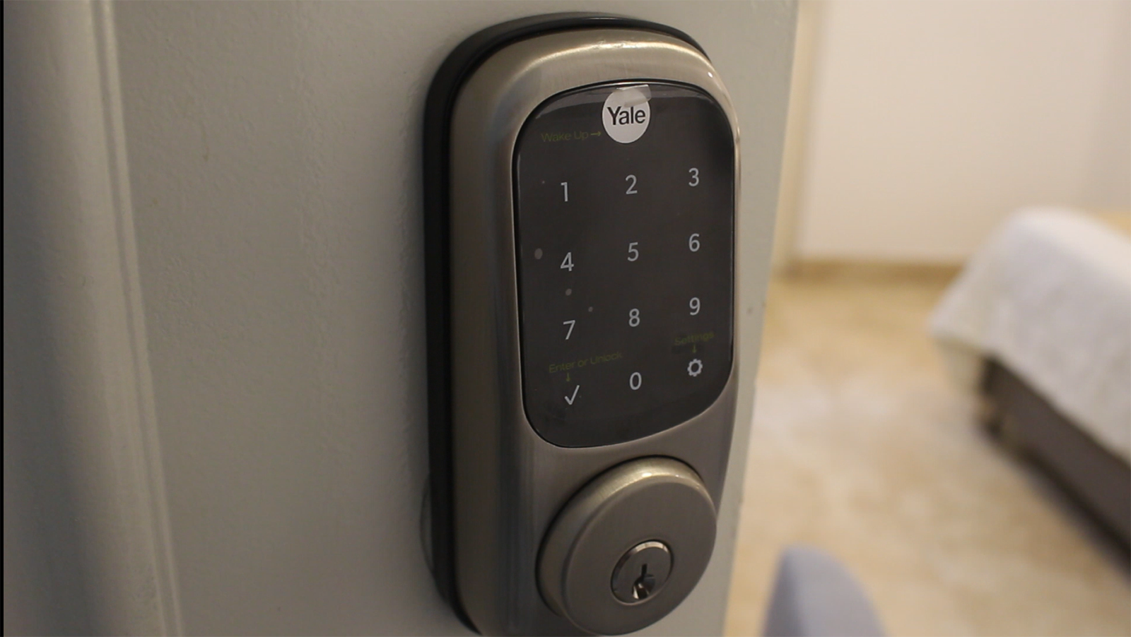 Cerradura inteligente gris con teclado en una puerta blanca.