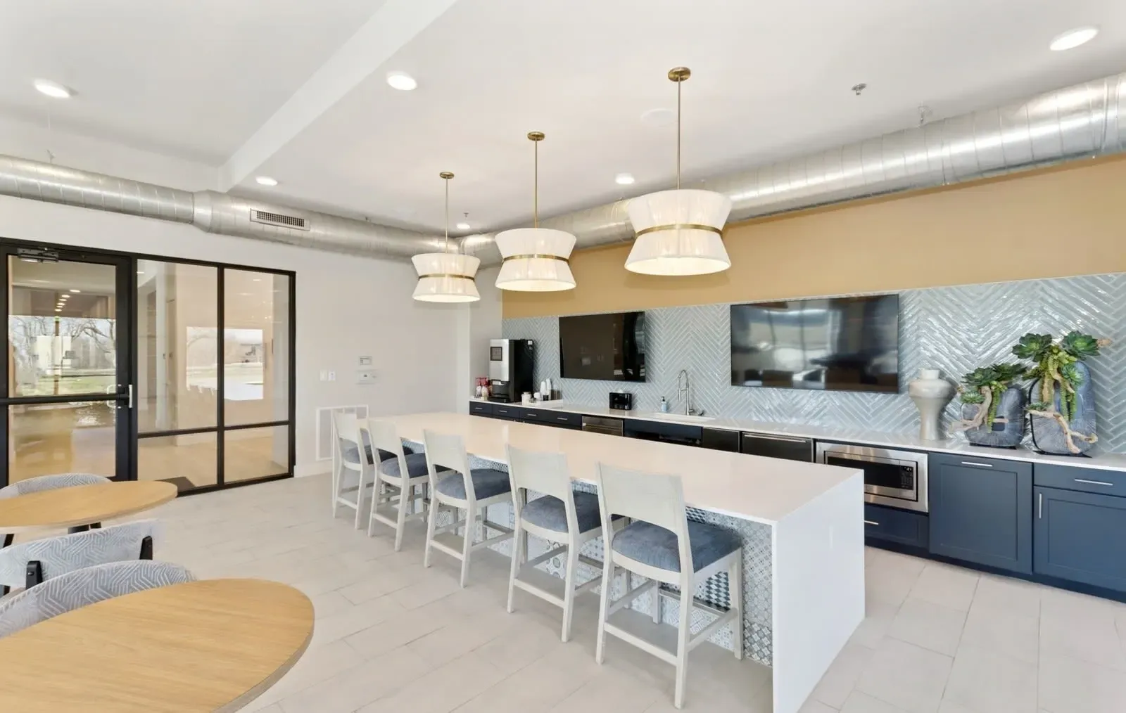 Modern community kitchen with long island, bar stools, and a mounted TV. Take a look at our stylish two-bedroom apartments in Rowlett, TX and see what makes them stand out—contact us today.