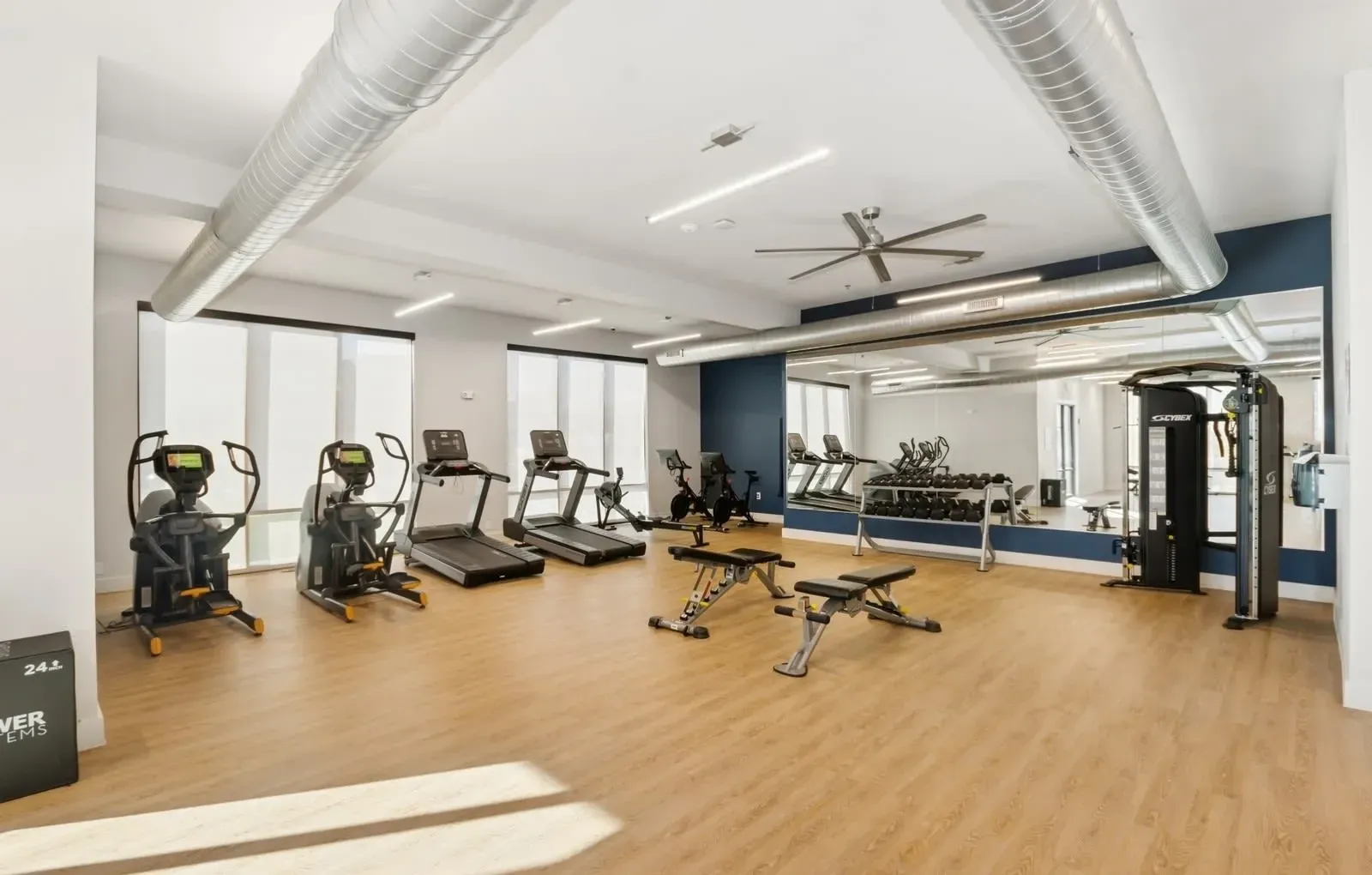 Bright apartment fitness center with cardio machines, free weights, and a large wall mirror. Explore apartments for rent in Rowlett, TX near Lake Ray Hubbard and picture your weekends—learn more today.