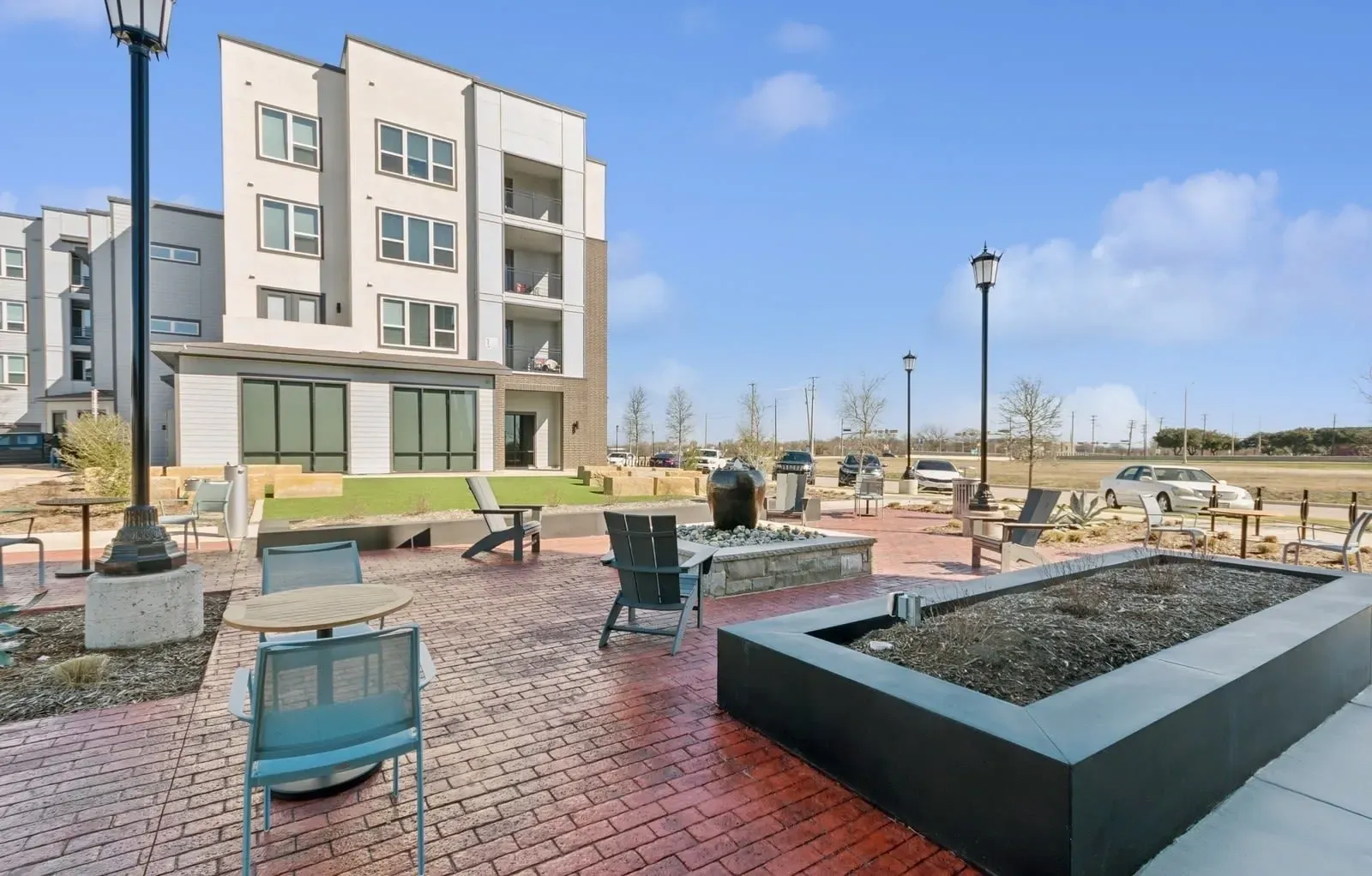 Exterior community courtyard with seating, a fire pit, and a modern apartment building in the background. Enjoy easy access from apartments near DART rail Rowlett, TX—find your ideal home today.