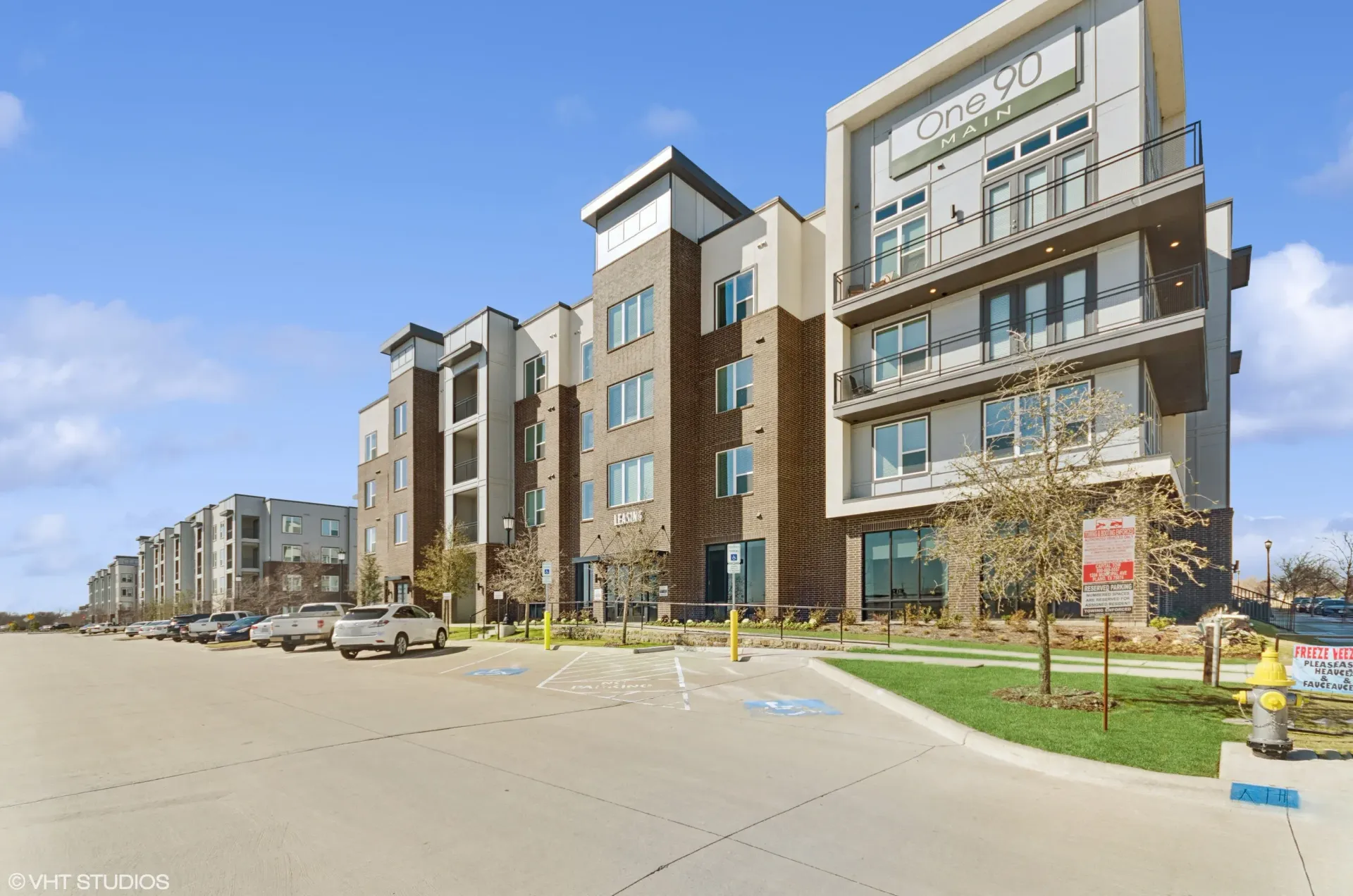 Exterior view of a modern apartment building with balconies and a parking lot. Commute with ease from apartments near I-30 Rowlett TX—explore your options and schedule a visit.
