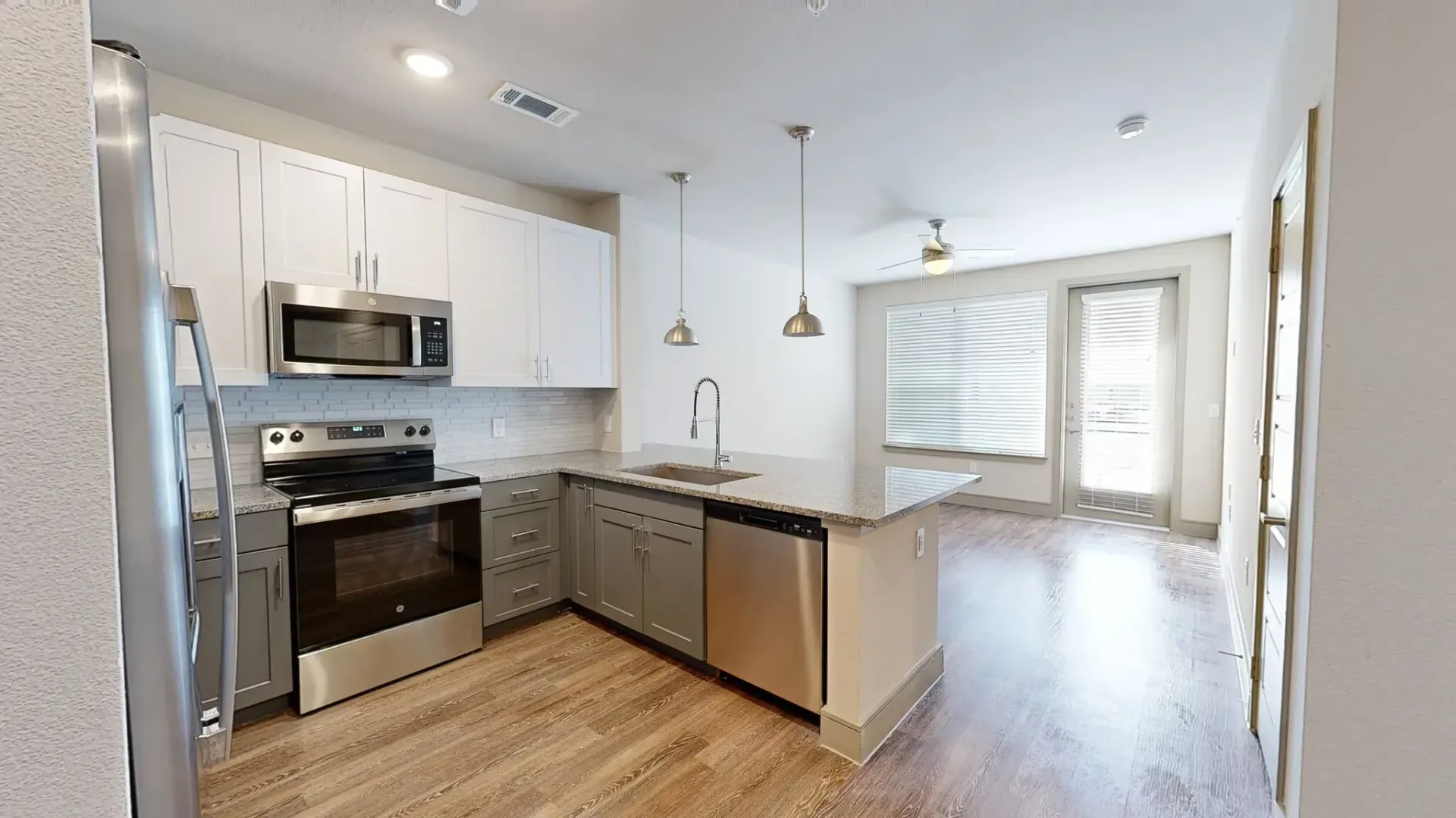 Open-concept kitchen with stainless steel appliances, island, and granite countertops. Explore flexible layouts in our two-bedroom apartments in Rowlett, TX—schedule a visit today.