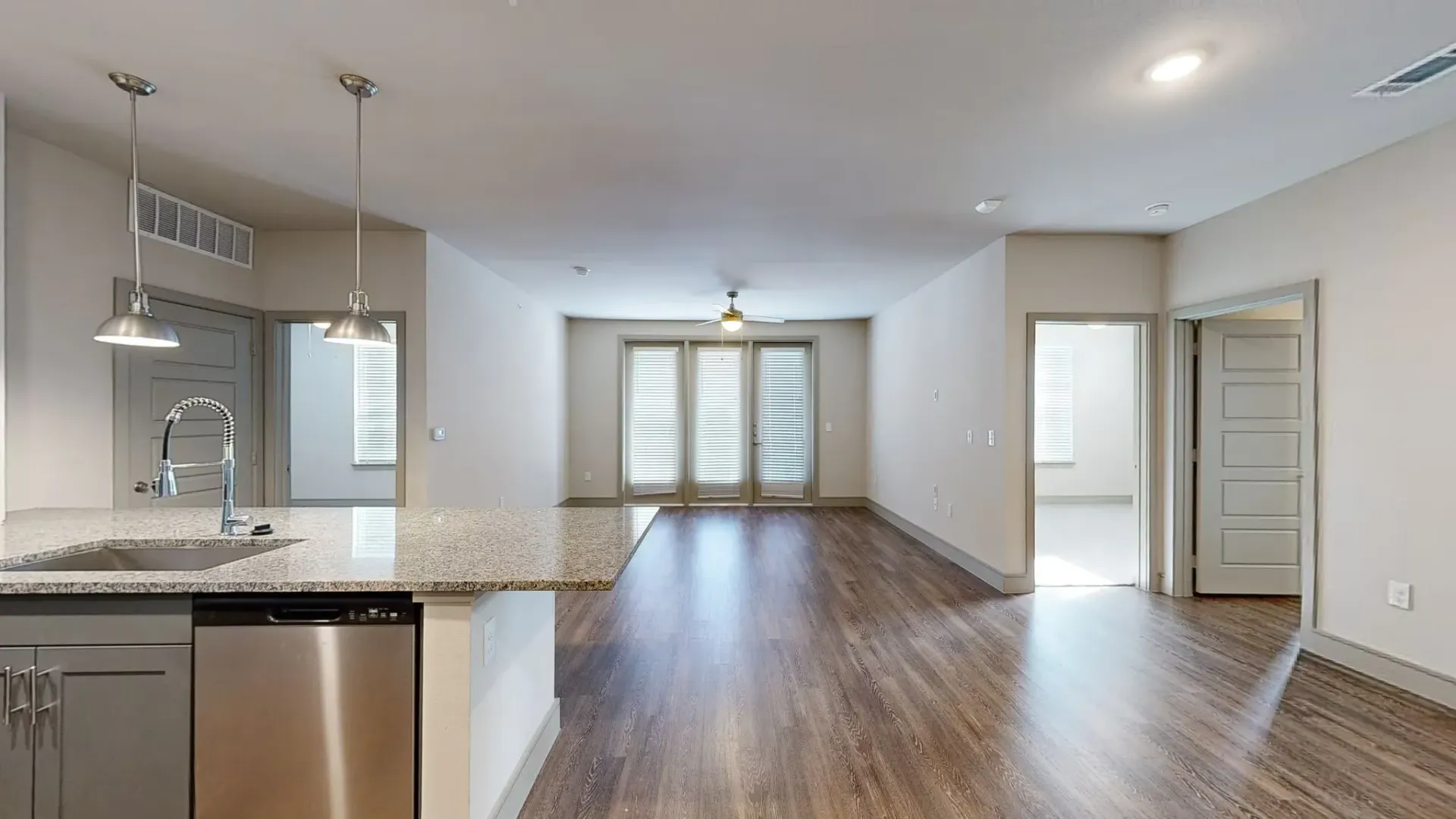 Open-concept kitchen with island, sink, and dishwasher overlooking the living area. See how spacious living feels in our three-bedroom apartments in Rowlett, TX—contact us to learn more.