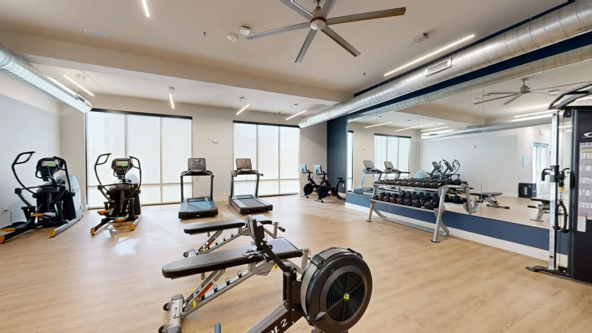 Well-lit community gym with cardio machines, free weights, and mirrors. Discover vibrant living at apartments in downtown Rowlett, TX—schedule your visit to see more.