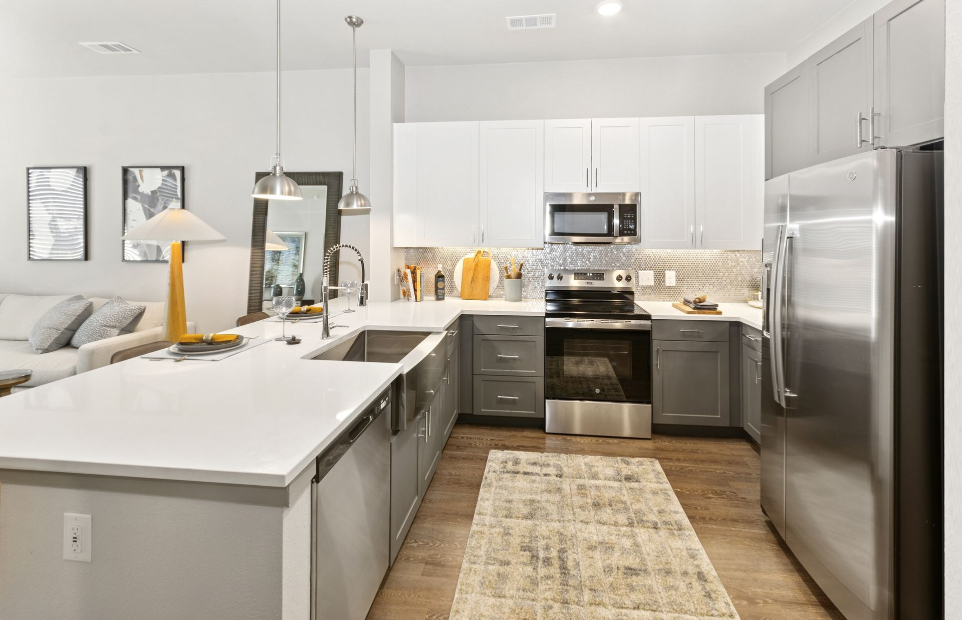 Bright modern kitchen with gray cabinets, stainless appliances, white island, and a beige runner rug