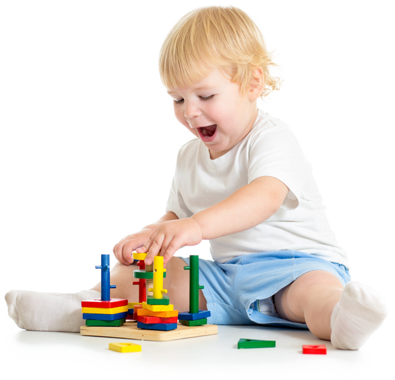 A little boy is sitting on the floor playing with a stacking toy.