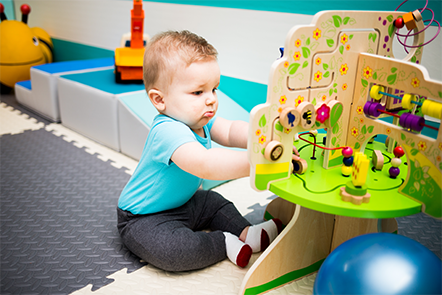 A baby is sitting on the floor playing with a wooden toy.