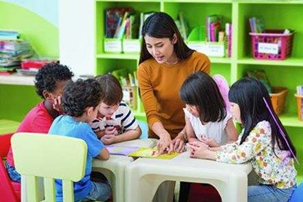 A teacher is teaching a group of children in a classroom.
