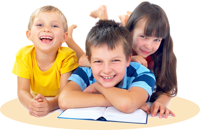 A boy and two girls are laying on a table with a book.