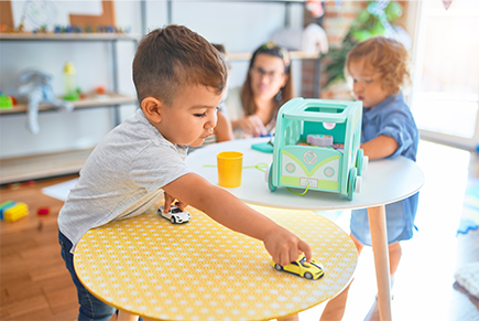 A young boy is playing with a toy car on a table.