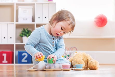 A little girl is sitting on the floor playing with toys.
