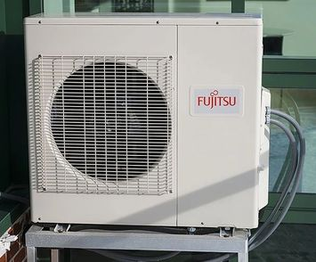A fujitsu air conditioner is sitting on a metal stand.