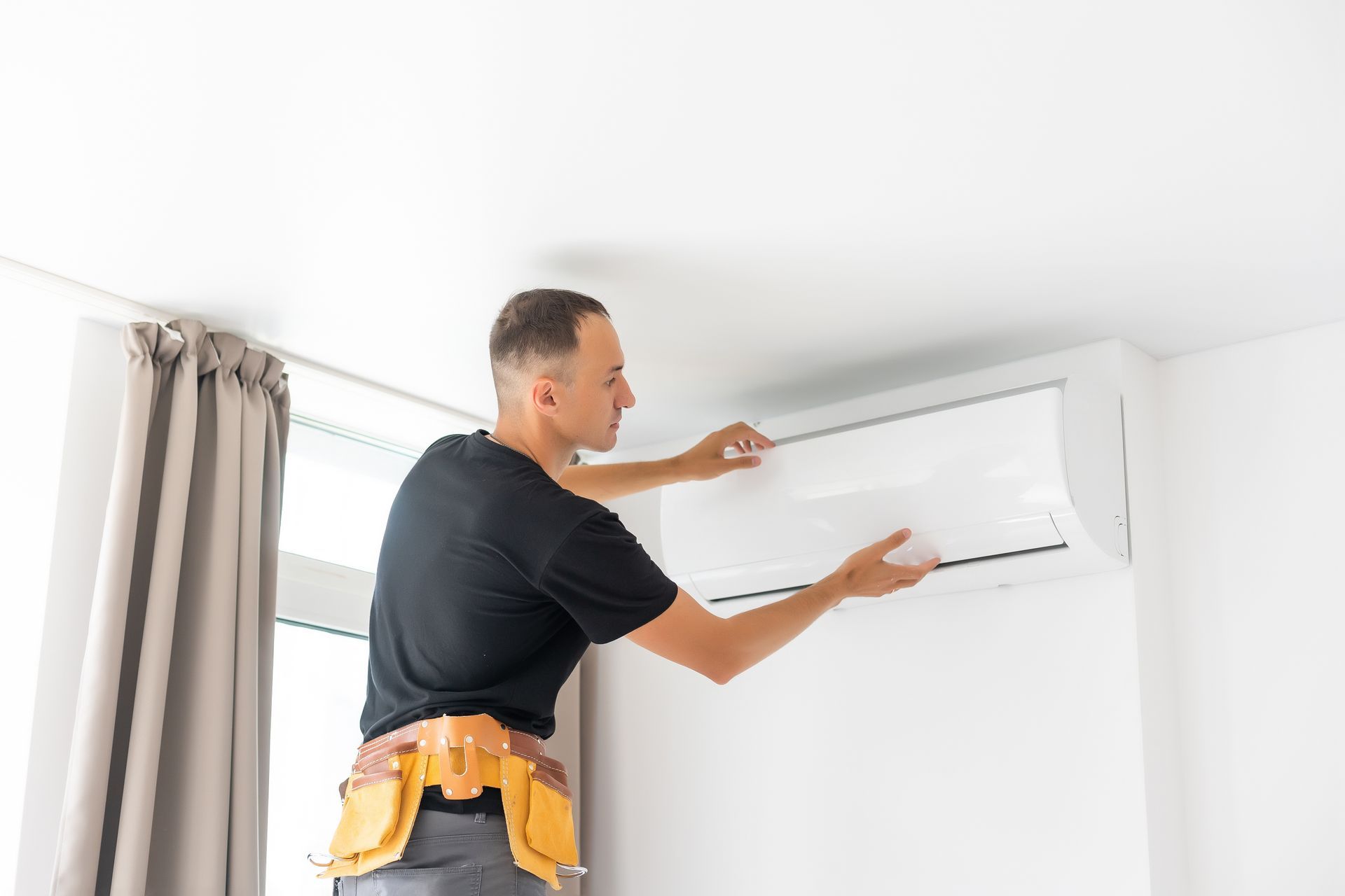 A man is installing an air conditioner in a room.