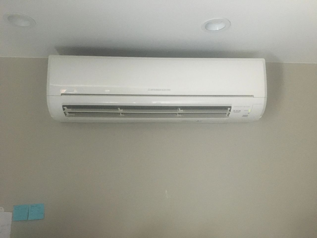 A white air conditioner is hanging from the ceiling in a room.
