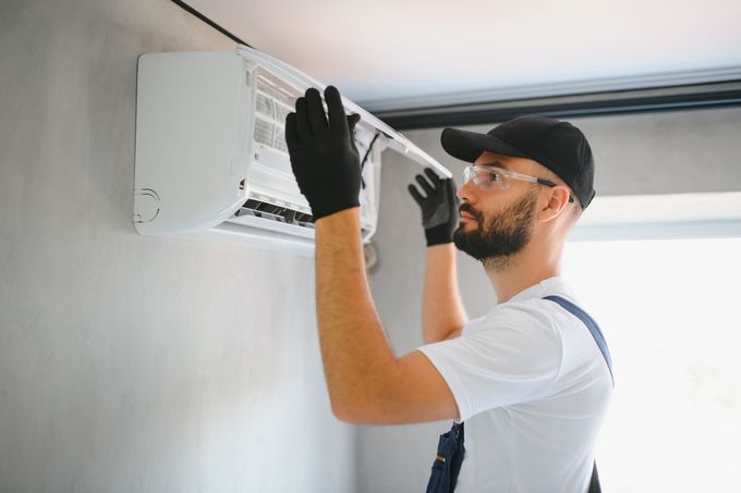 A man is installing an air conditioner on a wall.