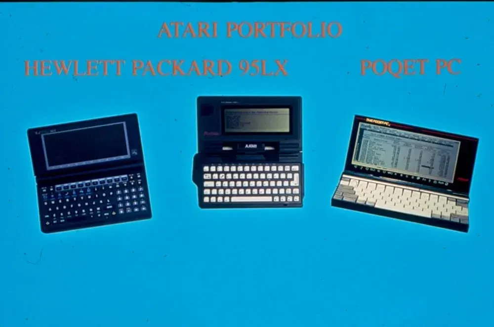 Three atari portfolio laptops are shown on a blue background