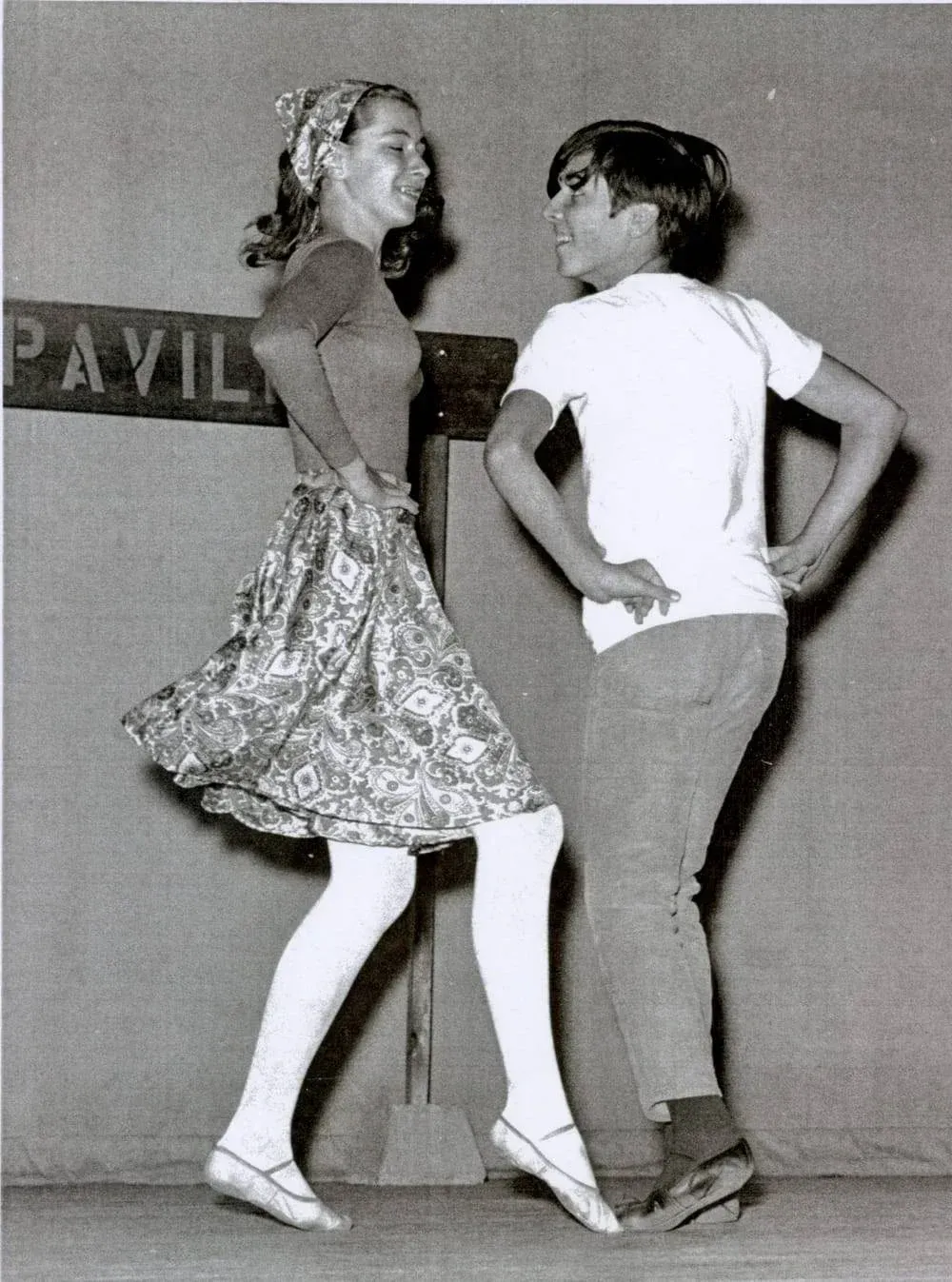 A boy and a girl are dancing in front of a sign that says pavillion