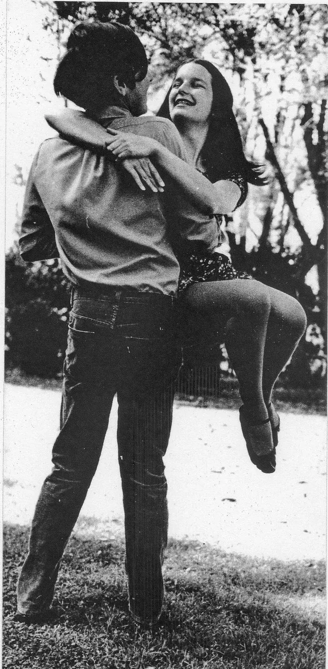 A man is carrying a woman in his arms in a black and white photo