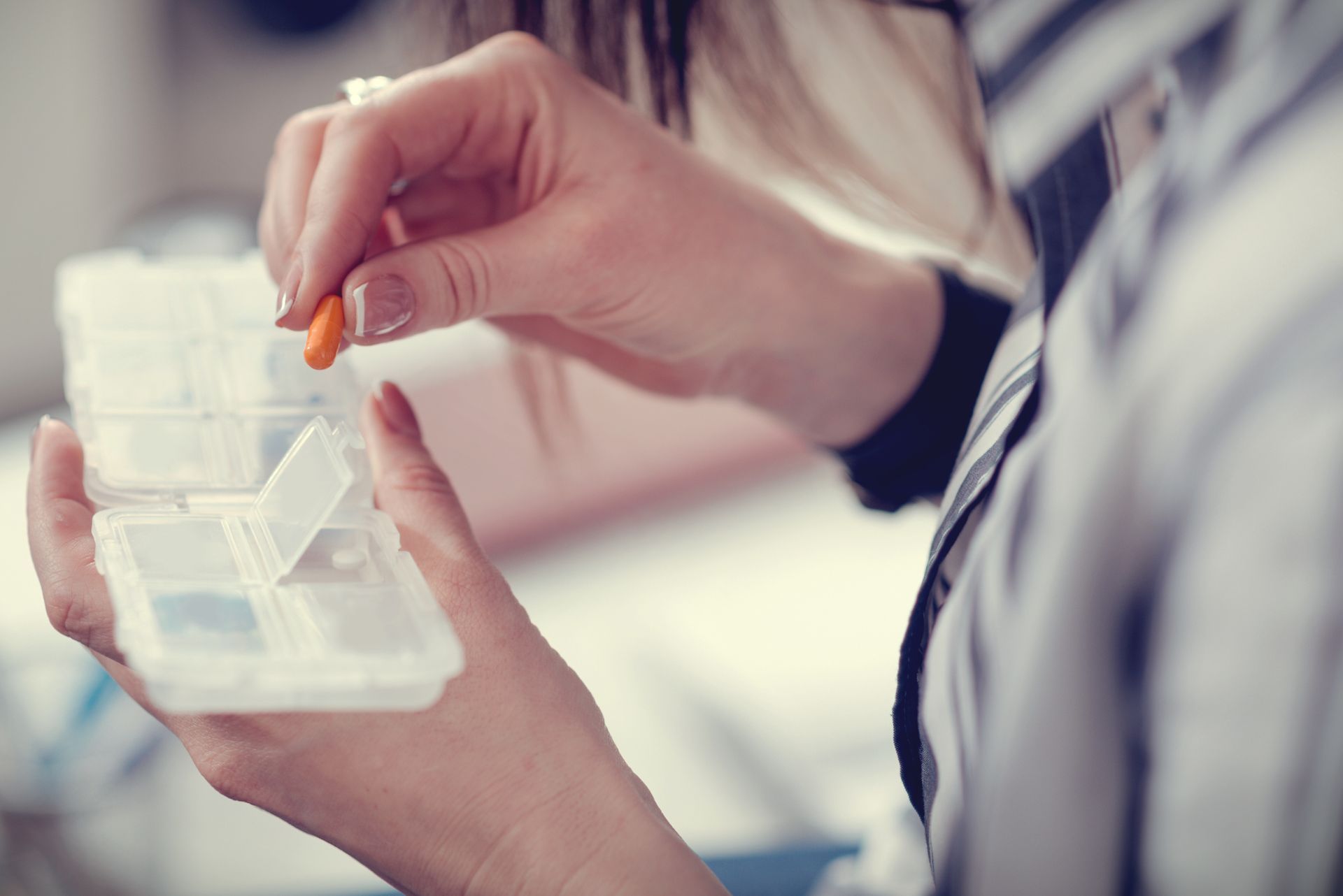 A woman is taking a pill out of a pill box.