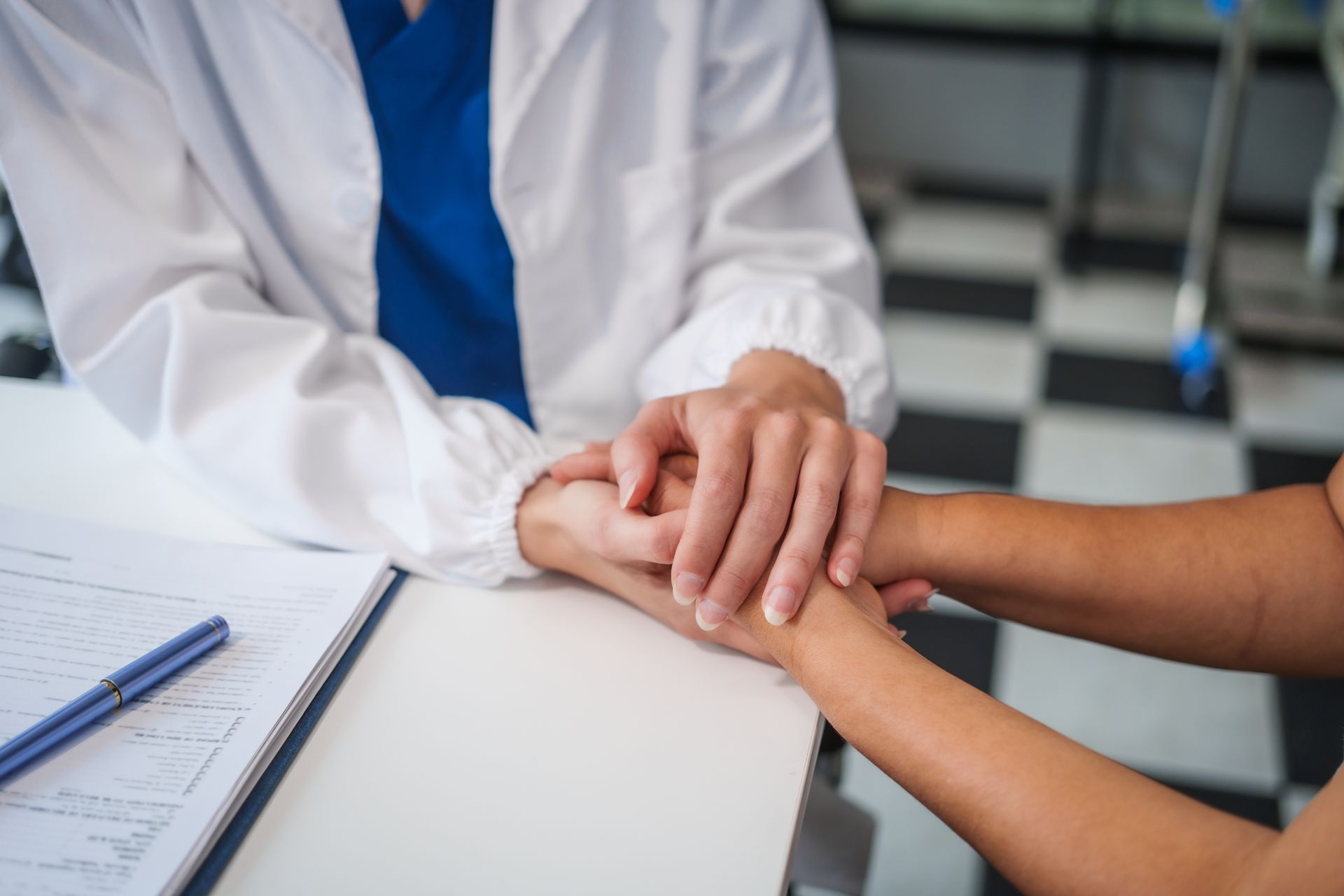 A doctor is holding the hand of a patient at a table.