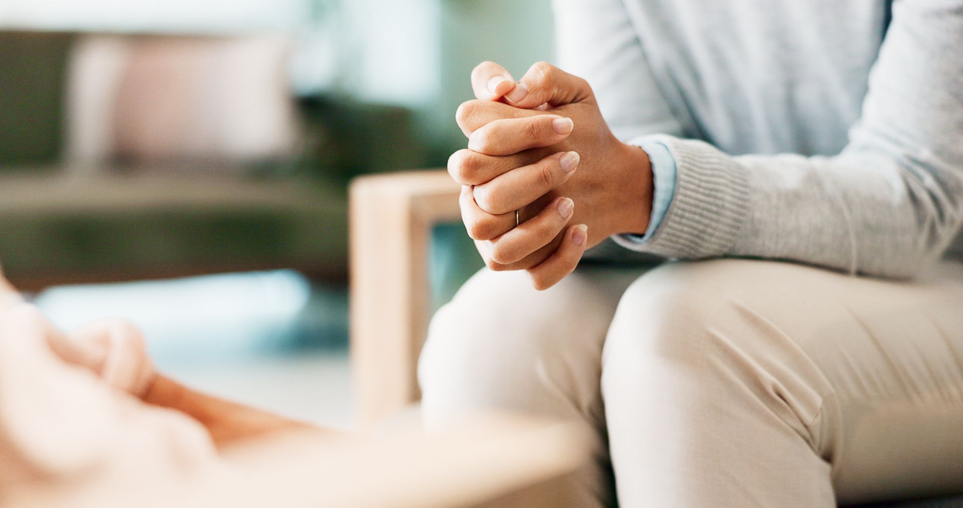 A person is sitting in a chair with their hands folded in prayer.