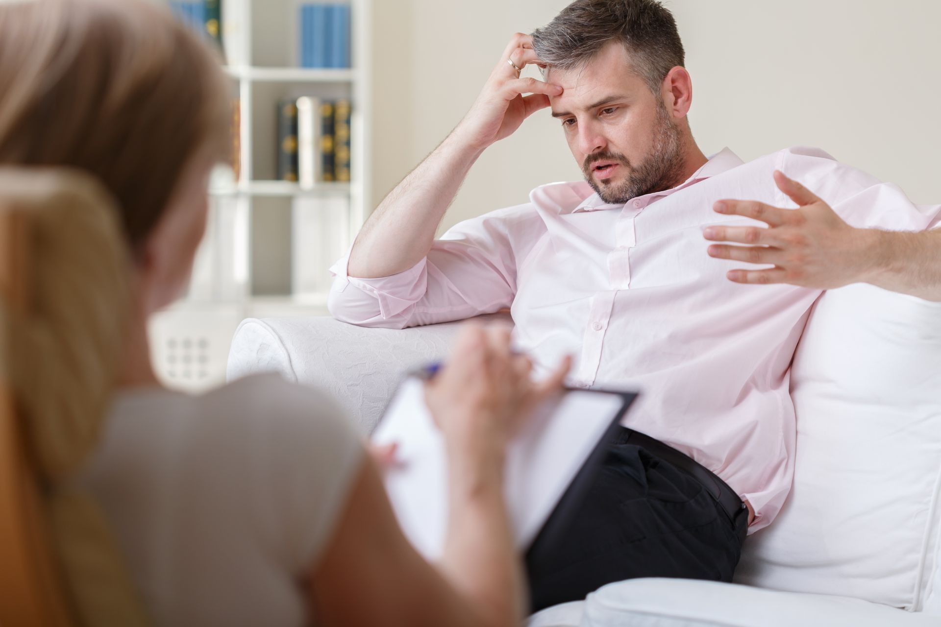 A man is sitting on a couch talking to a woman.