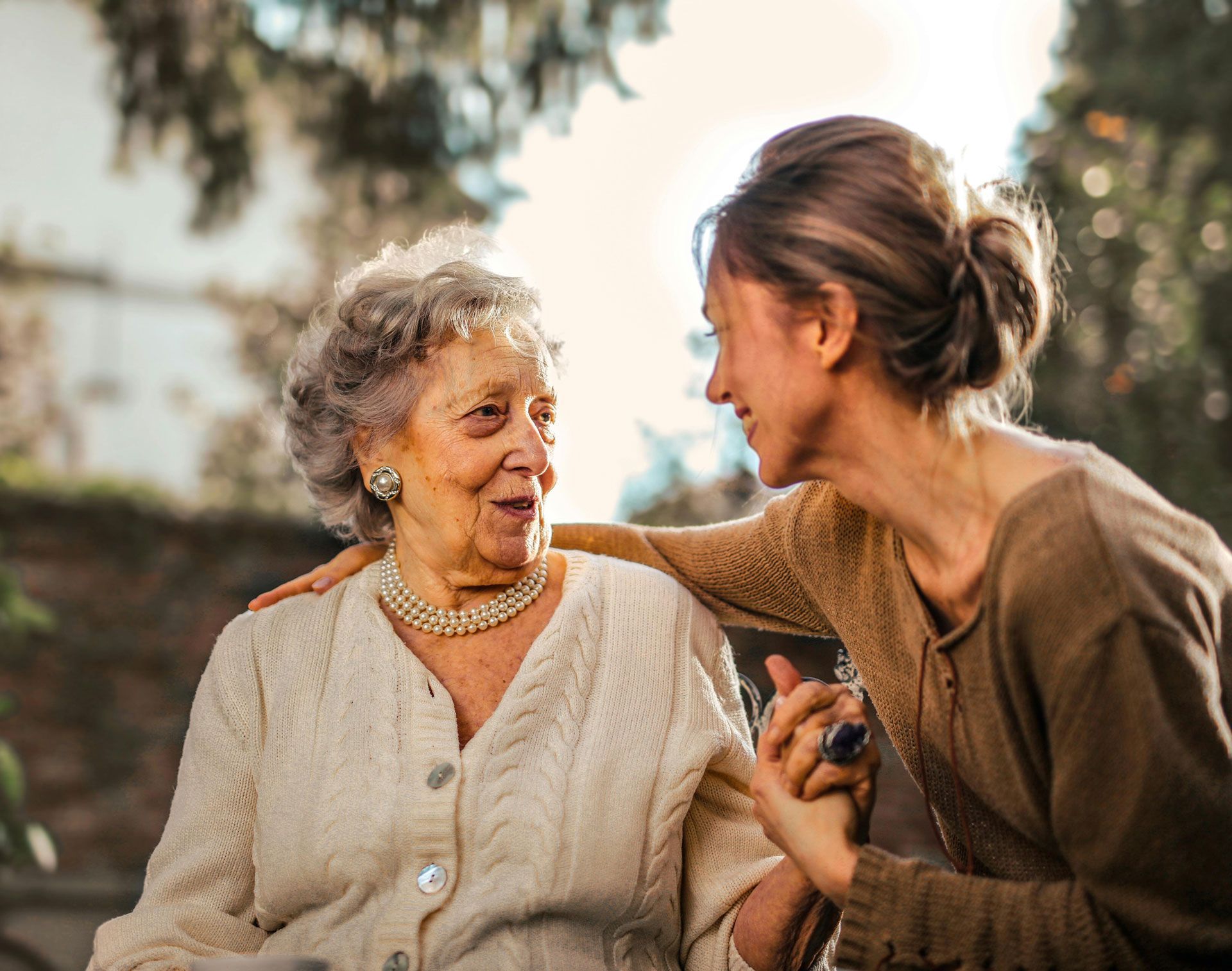 An elderly woman in a wheelchair is talking to a younger woman.