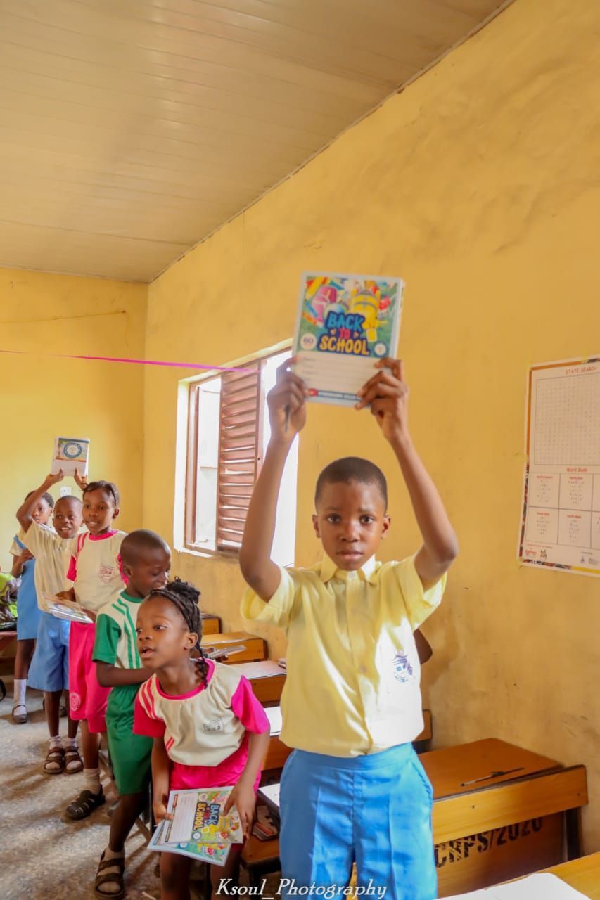 a boy is holding a book over his head in a classroom .