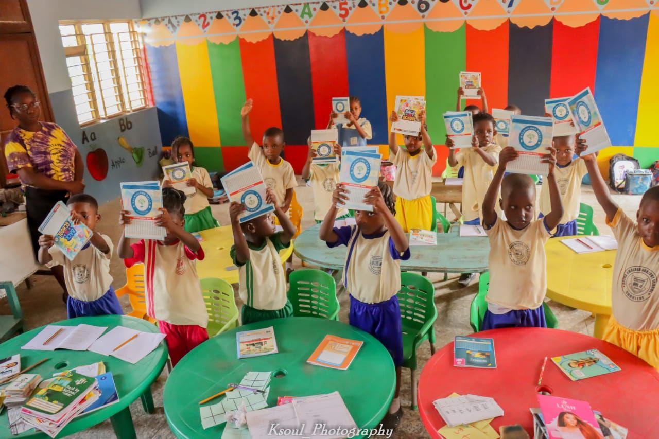 a group of children are holding up books in a classroom .