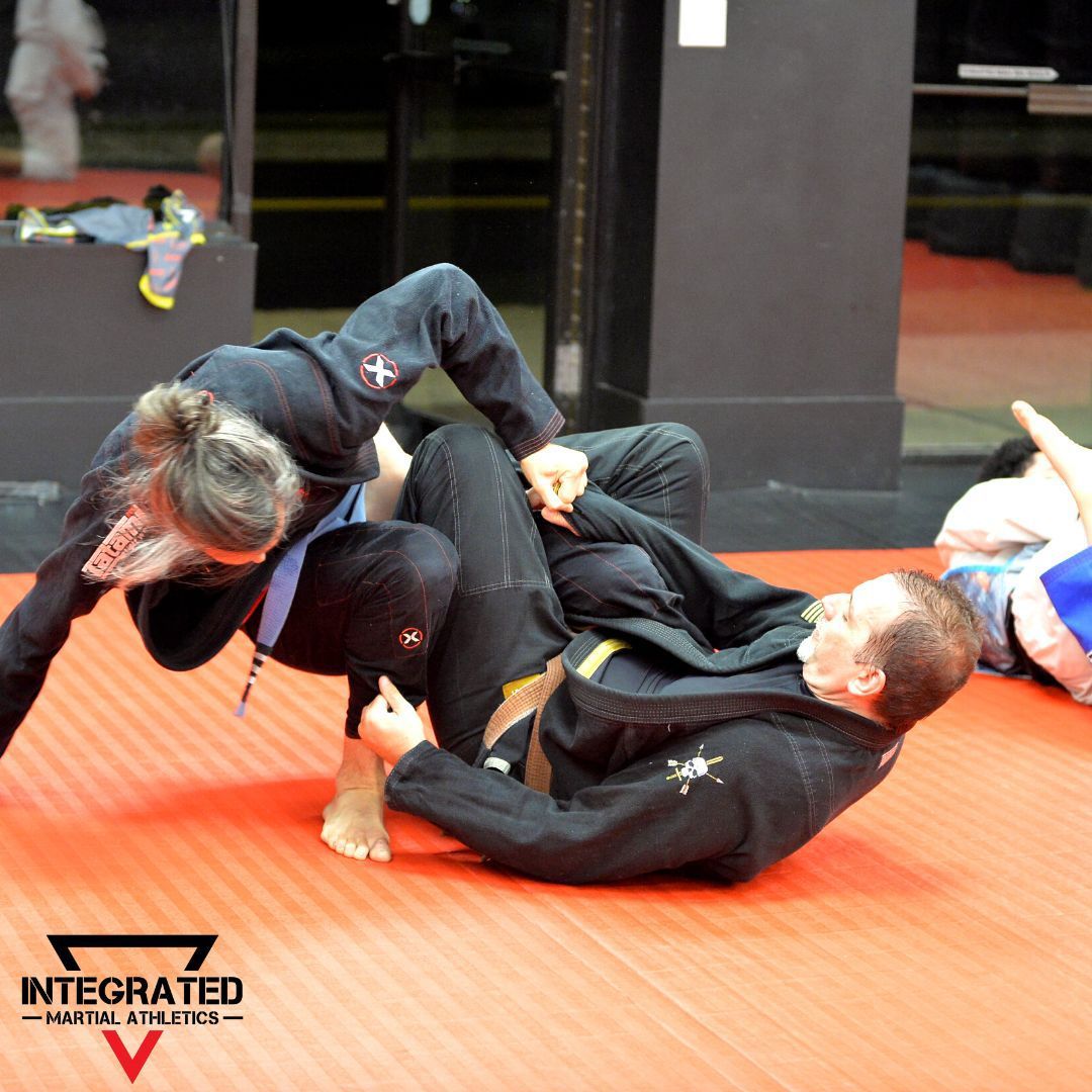 Two men are wrestling on a mat that says integrated