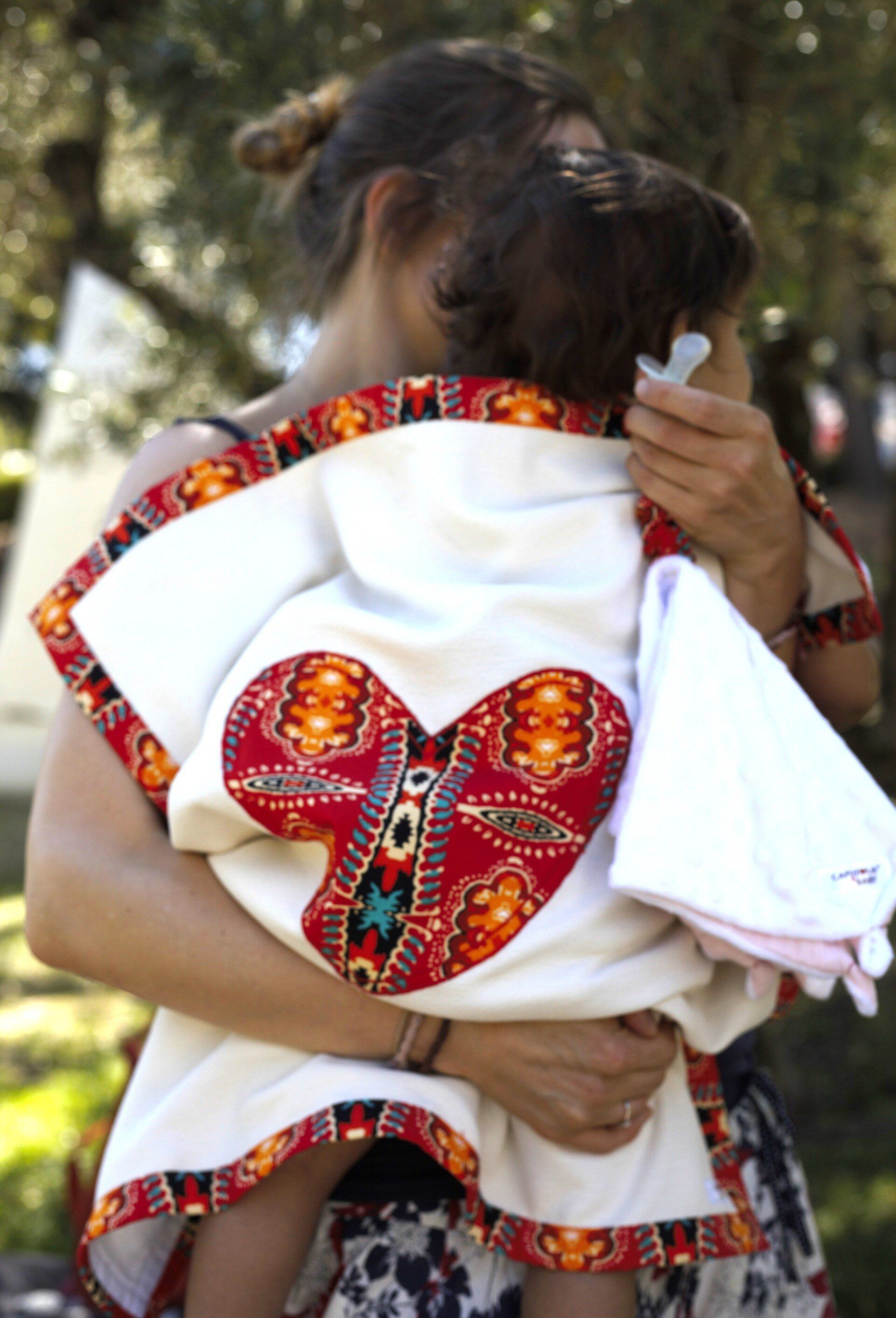 Uma mulher está segurando um bebê com um coração nas costas